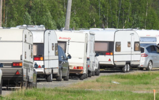 Autoja ja asuntovaunuja jonossa tiellä.